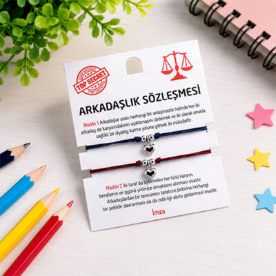 Renkli kalemler ve yıldız süsleri eşliğinde ahşap masada sergilenen arkadaşlık sözleşmesi bileklik seti
