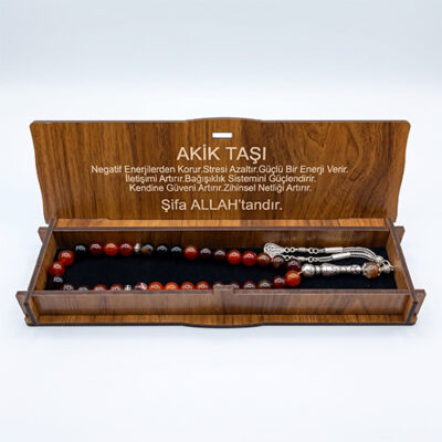Kapağında akik taşının faydaları yazılı olan ahşap hediye kutusu içinde siyah sünger üzerinde yatan akik tesbih.